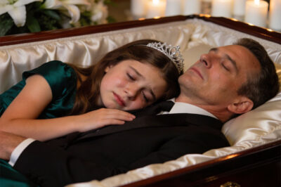 An 8-year-old girl refused to leave her father’s casket, standing there in silence long after everyone else had stepped away… until, without warning, something happened that made the entire room go still—and no one could explain why.